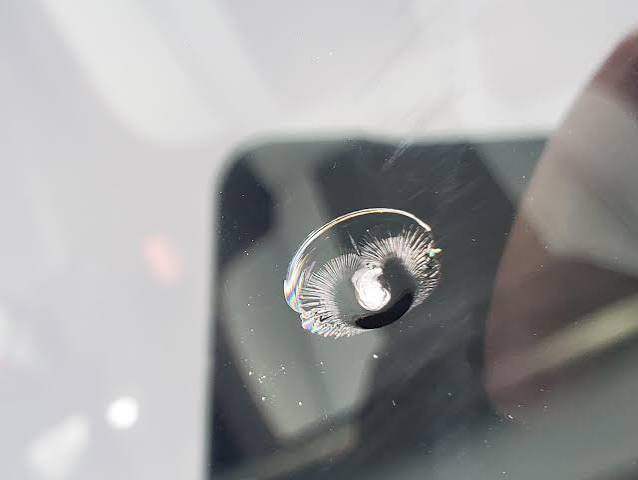 Bull's eye chip on windshield glass, tight circular impact crater