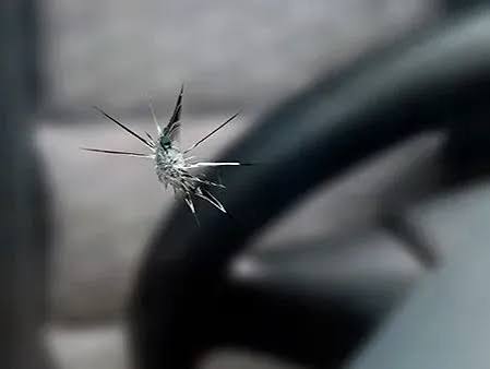 Star break chip pattern on windshield glass, central impact point with radiating legs
